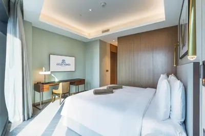 a hotel room with a white bed and a desk at Deluxe Address Opera Home with Full Sea View in Dubai