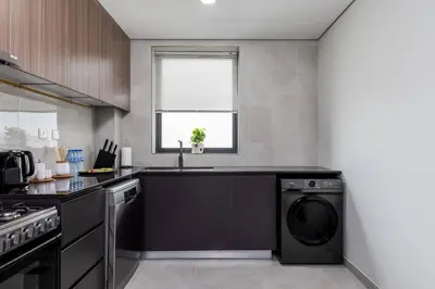 a kitchen with a washer and dryer in it at Waves - Stylish 1BR Close to IMG World & Global Village in Dubai