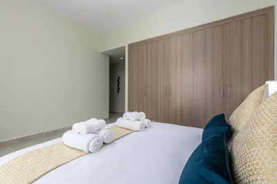 a bedroom with a white bed with towels on it at Waves - Stylish 1BR Close to IMG World & Global Village in Dubai