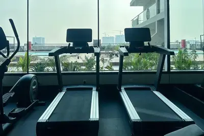 a gym with two treadmills in front of a window at Waves - Stylish 1BR Close to IMG World & Global Village in Dubai