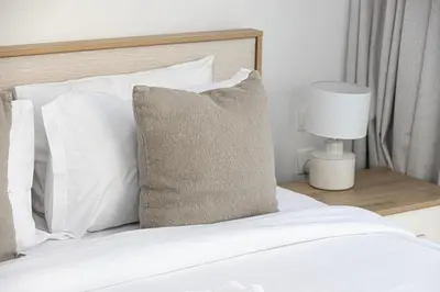 a bed with white pillows and a table with a lamp at Luxurious 1BR in Court Tower Business Bay in Dubai