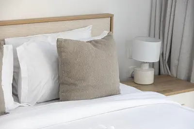a bed with white pillows and a table with a lamp at Luxurious 1BR in Court Tower Business Bay in Dubai