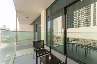 a balcony with a chair and tables on a building at HAVN - Smart Home Studio in Oxford Terraces, JVC in Dubai