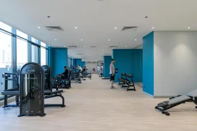 a large room with treadmills and people in a gym at HAVN - 1 Bedroom Unit in Azizi Riviera, Meydan in Dubai