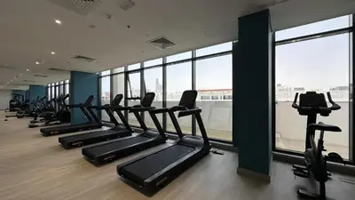 a gym with a row of treadmills and windows at HAVN - 1 Bedroom Apartment in Azizi Riviera in Dubai