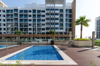 a swimming pool in front of a large building at HAVN - 1 Bedroom Apartment in Azizi Riviera in Dubai
