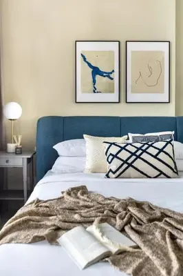 a bedroom with a bed with a blue headboard and two pictures at Stunning Burj Views - Highest Infiniti Pool in Dubai