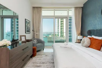 a bedroom with a large bed and a desk and window at Sunrise Bay Tower 2 - Beachfront Spectacular Two Bedroom with Private Beach Access in Dubai