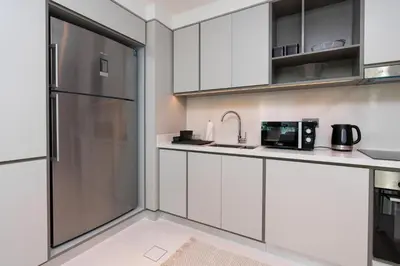 a kitchen with white cabinets and a stainless steel refrigerator at Sunrise Bay Tower 2 - Beachfront Spectacular Two Bedroom with Private Beach Access in Dubai
