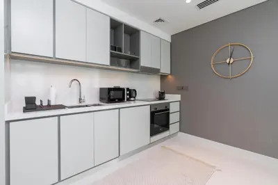 a kitchen with white cabinets and a clock on the wall at Sunrise Bay Tower 2 - Beachfront Spectacular Two Bedroom with Private Beach Access in Dubai