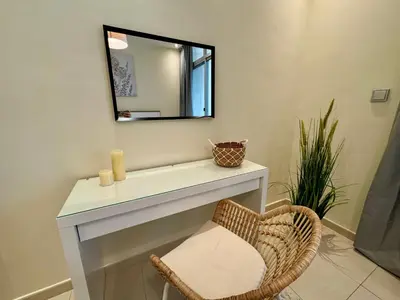 a mirror above a white vanity with a chair at Modern 1BR with Balcony, Pool and Gym, Dubai Marina in Dubai
