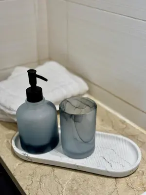 a bottle of soap and a cup on a plate at Modern 1BR with Balcony, Pool and Gym, Dubai Marina in Dubai