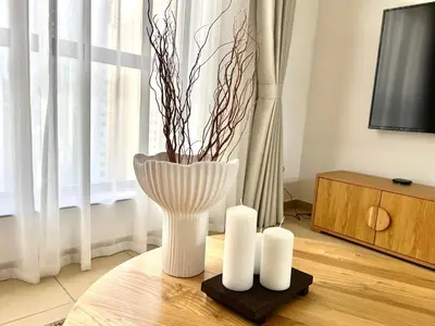 a white vase sitting on a table with two candles at High Floor 1BR Apartment with breathtaking sea views of AIN Dubai in Dubai