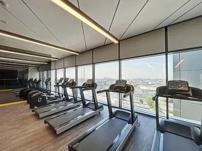 a row of treadmills in a gym with windows at Vacationer I Elegant 2 Bedroom I Business Bay I Central & Convenient I Aykon City Tower in Dubai