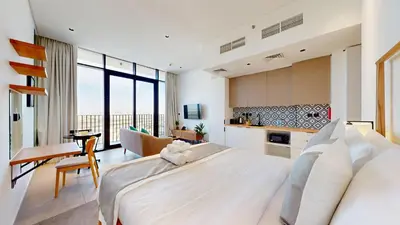 a bedroom with a large white bed and a kitchen at The Community Jumeirah Village in Dubai
