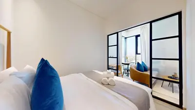 a bedroom with a white bed with blue pillows at The Community Jumeirah Village in Dubai
