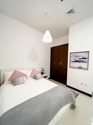 a bedroom with a large white bed with pink pillows at Beautiful studio apartment in Dubai