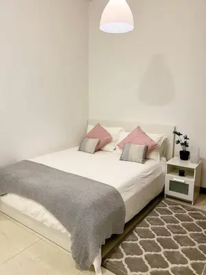 a bedroom with a white bed with pink pillows at Beautiful studio apartment in Dubai
