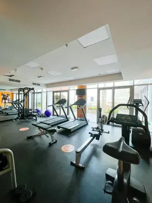 a gym with several treadmills and machines in a room at Beautiful studio apartment in Dubai