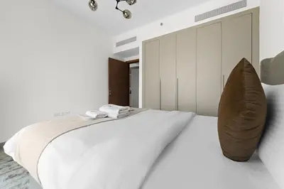 a white bedroom with a large bed with a pillow at StoneTree - Newly Furnished - Al Furjan in Dubai