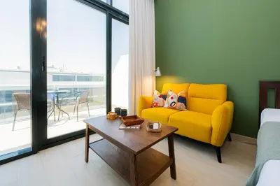 a living room with a yellow couch and a table at Elite Escape - 1 BHK Getaway in Azizi Riviera in Dubai