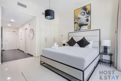 a white bedroom with a large bed and a hallway at Calm and Cozy Studio in Loreto 1A, Damac Hills in Dubai
