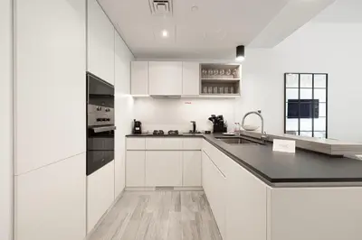 a kitchen with white cabinets and a black counter top at Sophisticated 1BR with Pool View in Belgravia Square JVC in Dubai