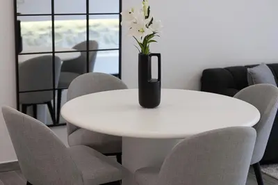 a white table with chairs and a vase with flowers on it at Sophisticated 1BR with Pool View in Belgravia Square JVC in Dubai