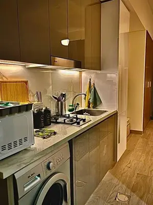 a kitchen with a sink and a washing machine at Chic and Cozy Studio in Dubai