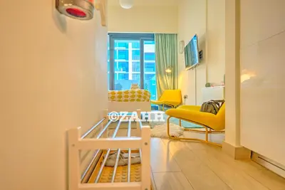a living room with yellow chairs and a window at Cozy Crib in Dubai