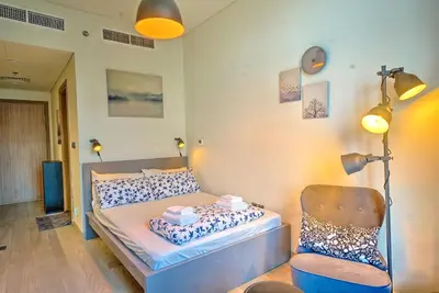 a bedroom with a bed with a chair and a lamp at Paradise Point in Dubai