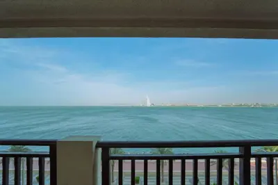 a view of the ocean from a balcony at Palm Paradise 1BR - Beachfront Escape with Pool, Gym, Parking & Balcony in Dubai