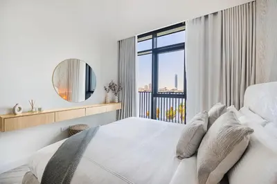 a white bedroom with a large bed and a window at Daniels 1BR at Creek Edge with Waterfront View in Dubai