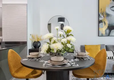 a black table with yellow chairs and white flowers on it at Elegant 1BR Getaway in Bella Rose, Al Barsha in Dubai