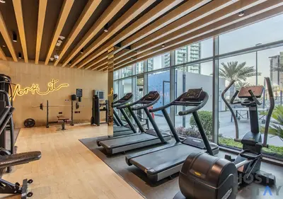 a gym with several treadmills and a large window at Elegant 1BR Getaway in Bella Rose, Al Barsha in Dubai