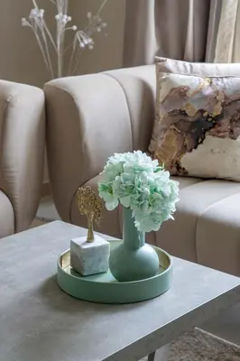 a table with a green vase with flowers on it at Frank Porter - Dunya Tower in Dubai