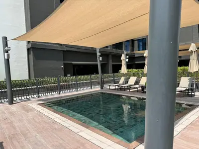 a swimming pool with chairs and an umbrella on a building at 1 Bedroom with Canal View - 15 Northside in Dubai