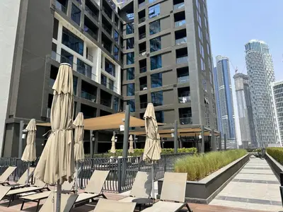 a group of chairs and umbrellas in front of a building at 1 Bedroom with Canal View - 15 Northside in Dubai