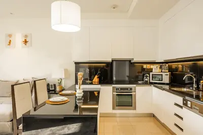 a kitchen with white cabinets and a dining table at Apartments in Address Dubai Marina Residences connected to Marina Mall in Dubai