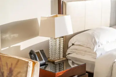 a lamp on a table next to a bed with a phone at Apartments in Address Dubai Marina Residences connected to Marina Mall in Dubai