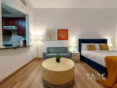 a bedroom with a bed and a table and a couch at Rare Holiday Homes - Mediterranean Cluster - Near Ibn Battuta Mall - Discovery Garden - Building# Med 49 - R213 in Dubai