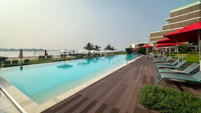 a swimming pool with chairs and umbrellas next to a building at Waves - Premium Seaside Retreat With Private Beach in Dubai