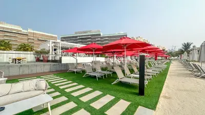 a row of chairs and red umbrellas on a patio at Waves - Premium Seaside Retreat With Private Beach in Dubai