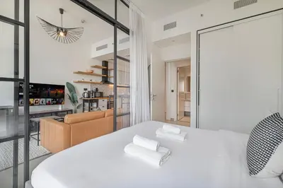 a bedroom with a white bed and a living room at Cozy 1BR Near Dubai Hills Park in Dubai