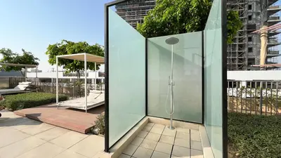 a shower in a glass enclosure in a yard at Cozy 1BR Near Dubai Hills Park in Dubai