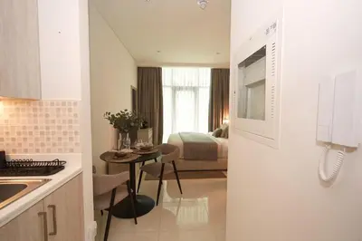 a kitchen with a table and a room with a bed at Comfy stylish studio on the Palm in Dubai