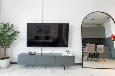 a living room with a mirror and a tv on a wall at Bespoke Holiday Homes - Mag Eye Residence in Dubai