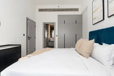 a bedroom with a large white bed with a blue headboard at Bespoke Holiday Homes - Mag Eye Residence in Dubai