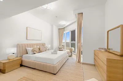 a white bedroom with a bed and a living room at Elegant 1 BR Apartment near Mall of the Emirates in Dubai