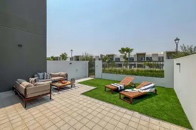 a patio with two couches and chairs on grass at Frank Porter - La Rosa 6 in Dubai